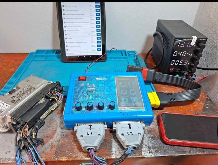 Equipo de electrónica automotriz sobre una mesa de trabajo, conectado a un módulo ECU, pantalla y fuente de alimentación